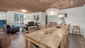 Un comedor amplio con una larga mesa de madera, varias sillas e iluminación colgante.