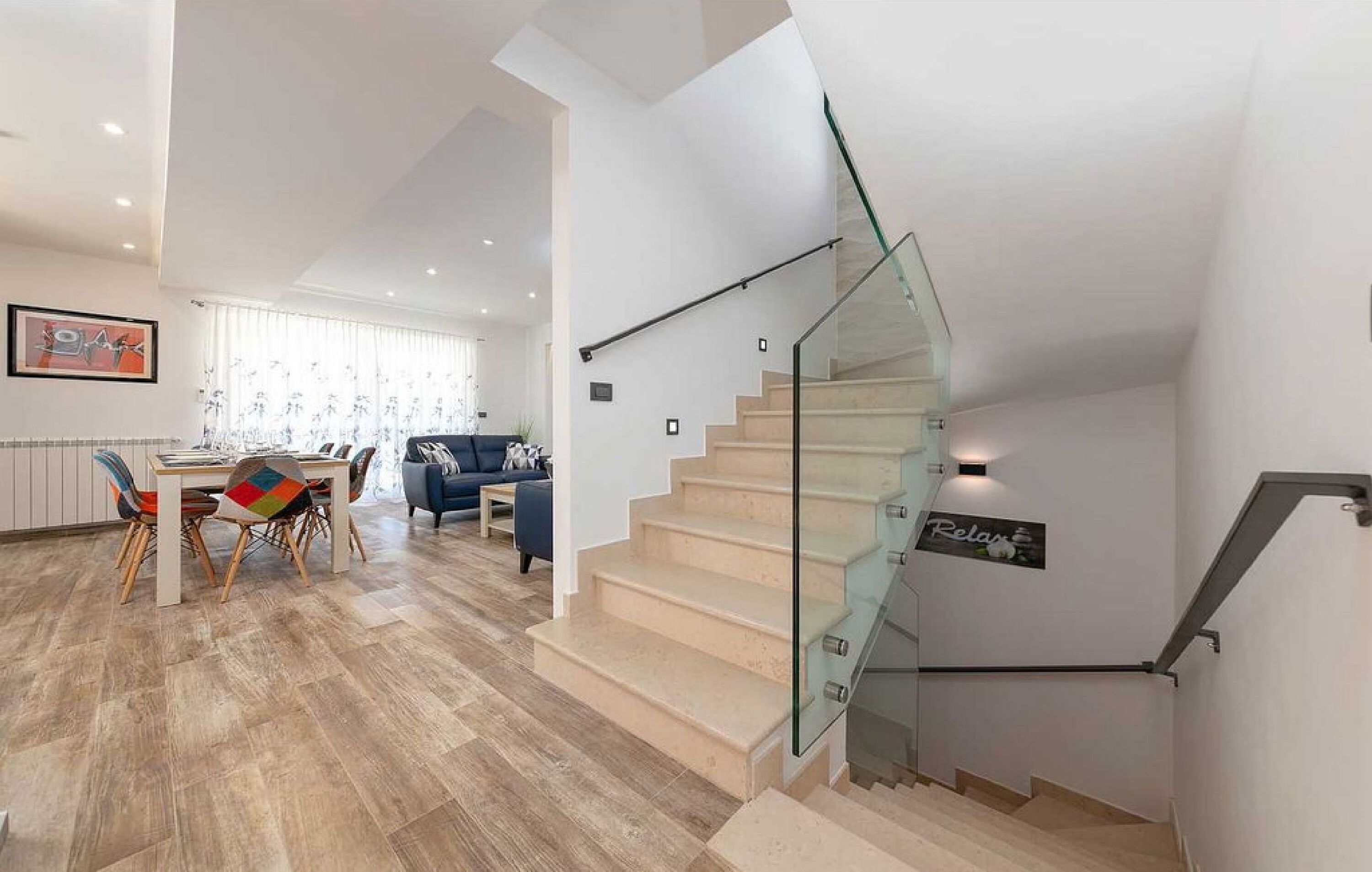 A modern interior with a staircase, a dining area, and a living space.