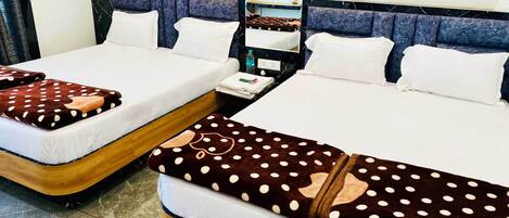 Two double beds with white linens, a marble-patterned headboard, a small bedside table with a bottle and a folded towel, and a mirror above the bed.