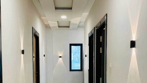 A hallway with a polished floor, recessed ceiling lights, and doors on both sides. - Hotel JK Palace (Khandwa)