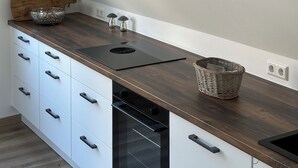 Eine moderne Küche mit einer Holzarbeitsplatte, einem eingebauten Backofen und weißen Schränken.
