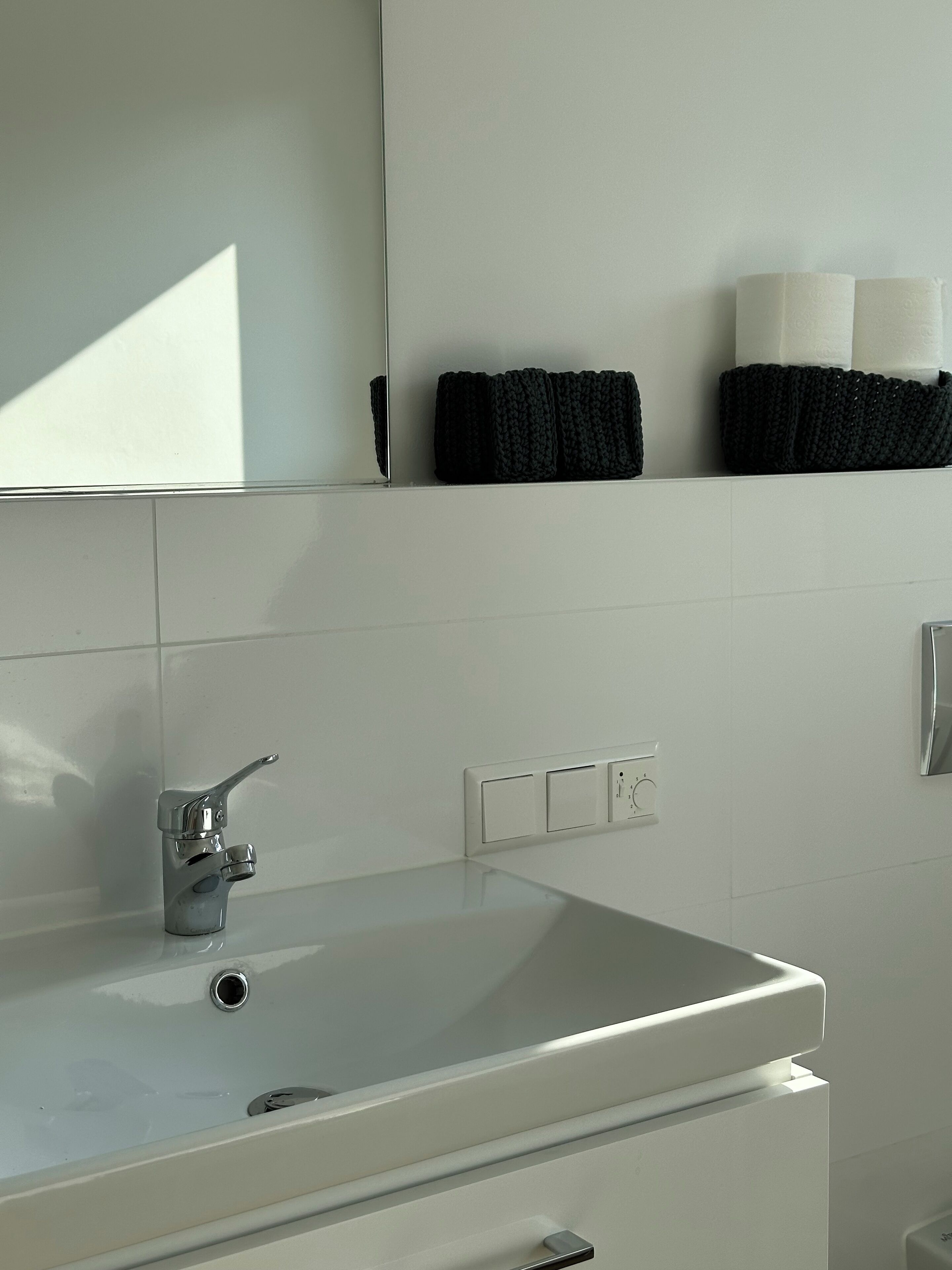 A bathroom with a white sink, a mirror, and a towel rack with black towels.