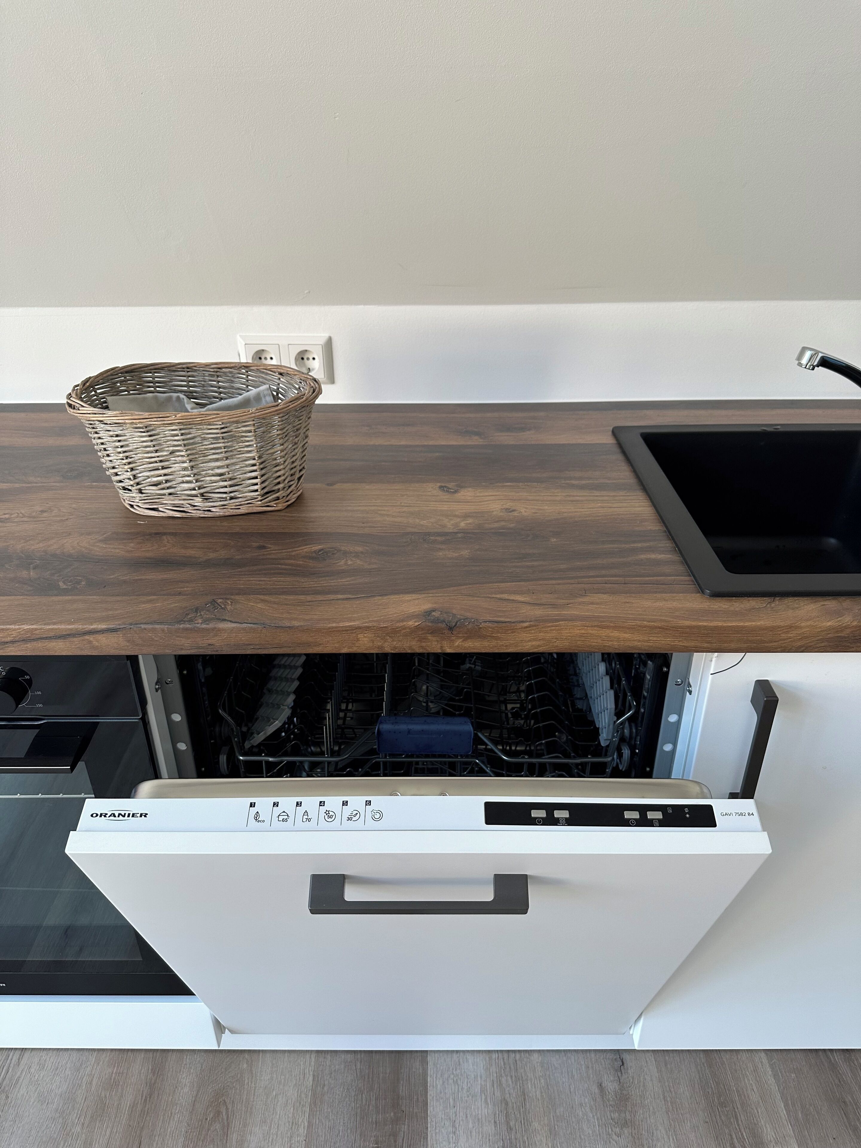 A kitchen with a dishwasher, a sink, and a wooden countertop.