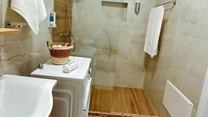 A modern bathroom with a shower, a sink, and a towel rack. - Charming Soleis Apartment With Balcony and Free Wifi (Tirana)