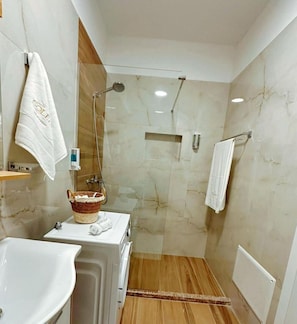 A modern bathroom with a shower, a sink, and a towel rack.