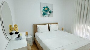 A bedroom with a bed, a bedside table, a mirror, and a wall-mounted artwork. - Charming Soleis Apartment With Balcony and Free Wifi (Tirana)