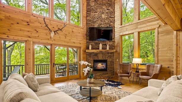 A cozy living room with a stone fireplace, large windows, and a comfortable seating area.