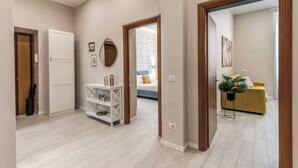 A spacious hallway with a white door, a white console table, and a yellow sofa in the background. - Newly renovated apartment in the heart of Rome. (Roma)