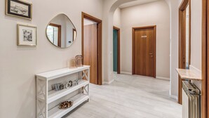 A hallway with a white console table, framed pictures, a mirror, and wooden doors. - Newly renovated apartment in the heart of Rome. (Roma)