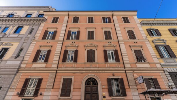 A multi-story building with a classic architectural style, featuring a central entrance with a decorative archway and multiple windows with shutters. - Newly renovated apartment in the heart of Rome. (Roma)