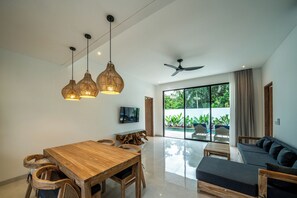 Uma sala de estar ampla com uma mesa de jantar de madeira, um sofá e um ventilador de teto.