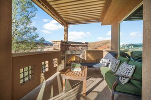 A patio with a stone fireplace, a wooden table, and a green sofa with patterned cushions. - Coral Sunset Amenity-filled! (Hurricane)