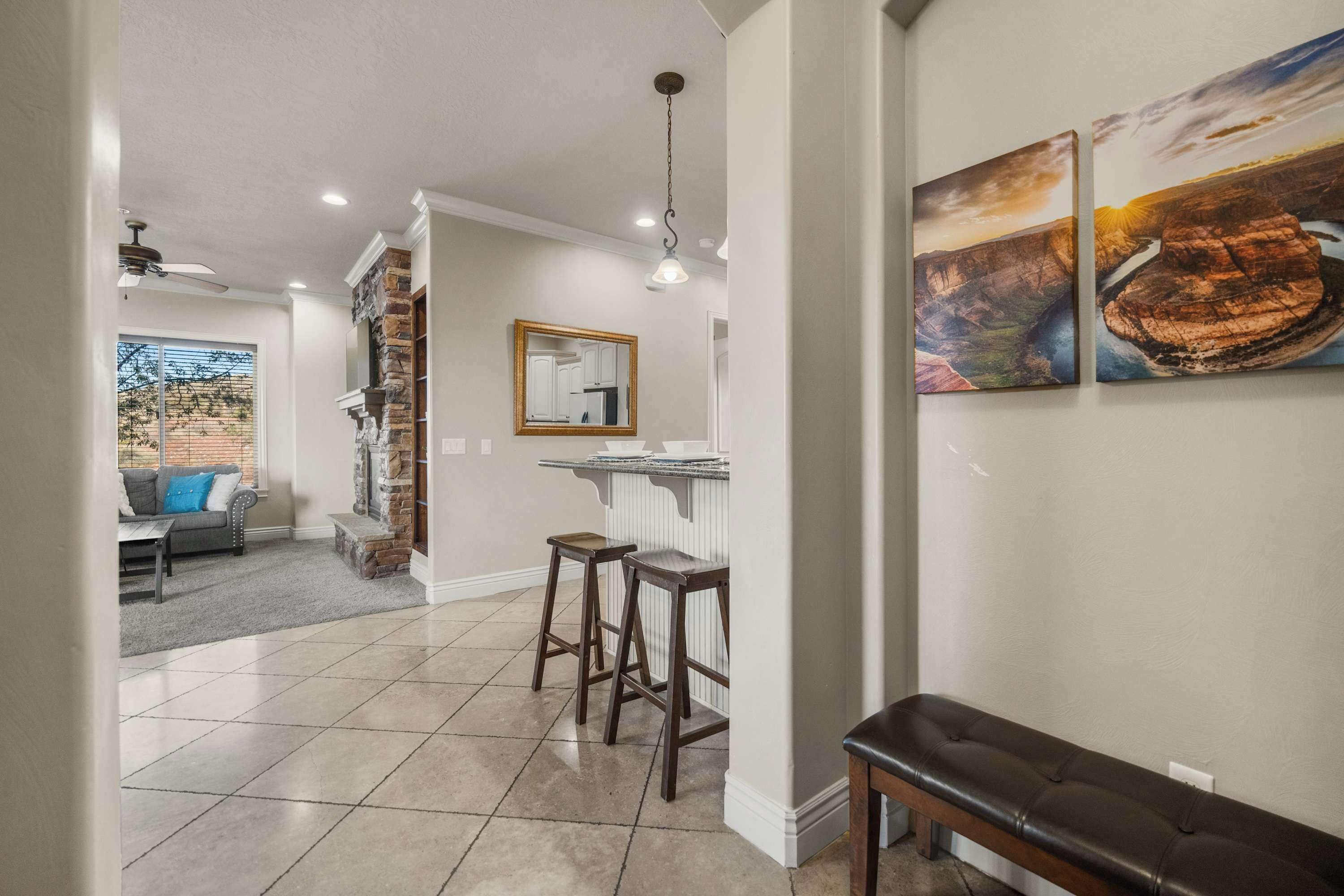 A modern kitchen with a stone accent wall, a bar area with stools, and a dining bench.