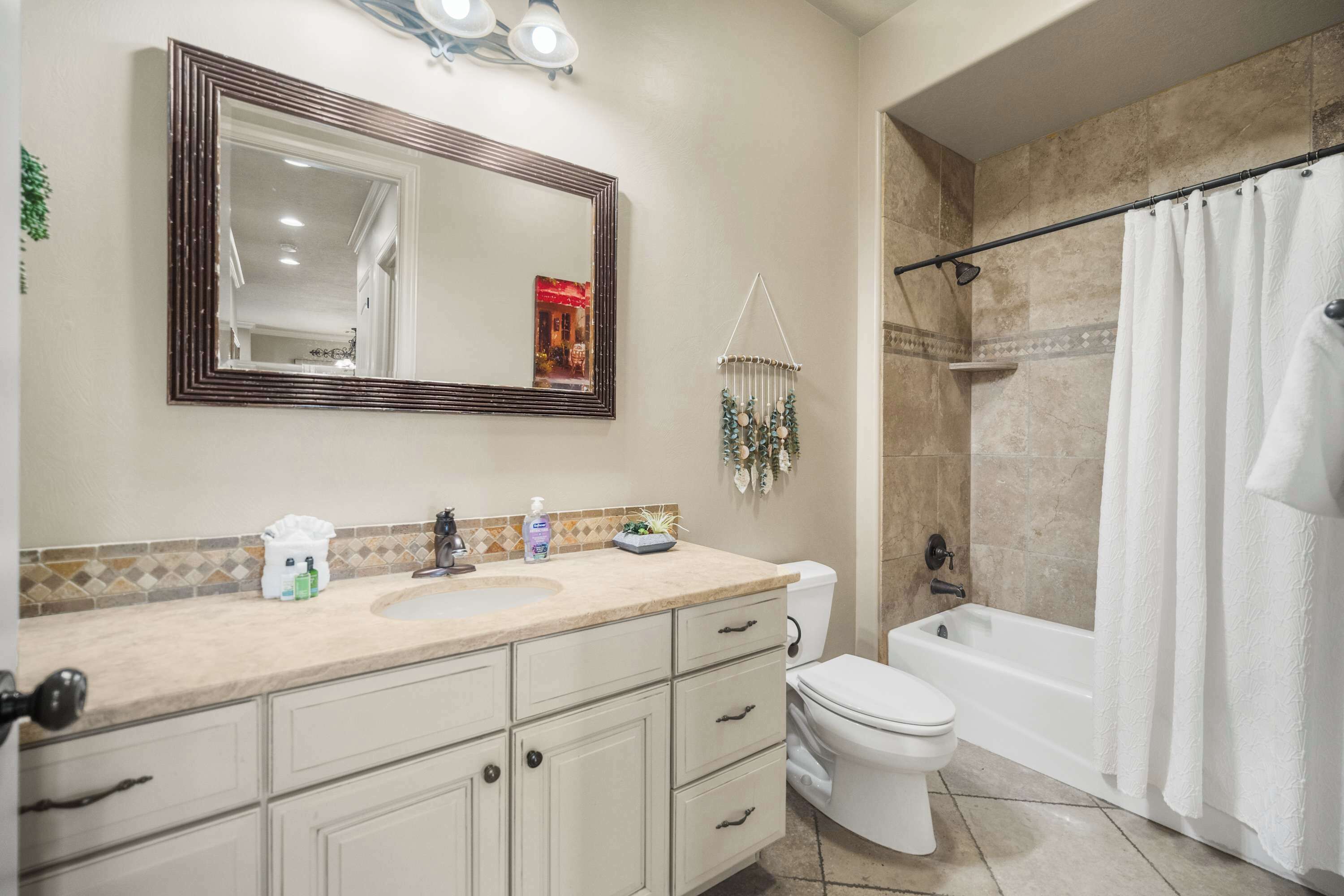 A bathroom with a sink, mirror, toilet, and bathtub.