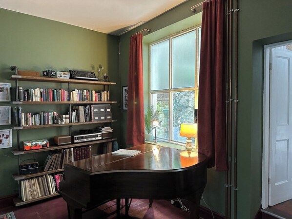 A room with a large desk, bookshelves, and a window with curtains. - Delightful House in the Heart of the Matlocks! (Matlock)