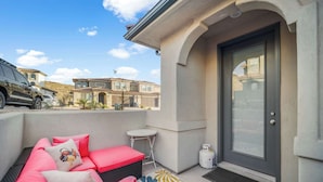 Un balcon avec un espace salon, une petite table et une porte.