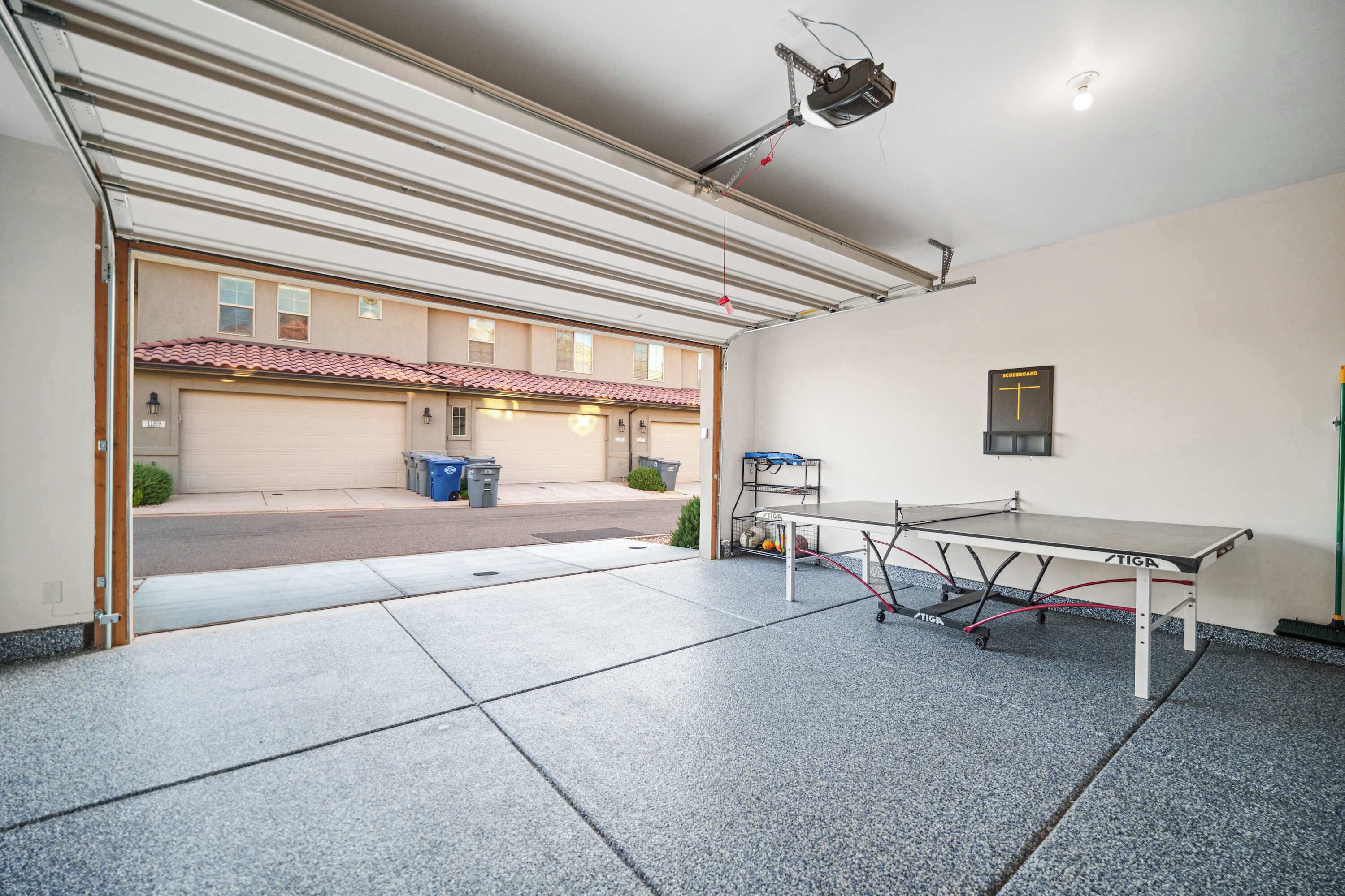 A covered outdoor area with a ping pong table, a projector, and a garage door.