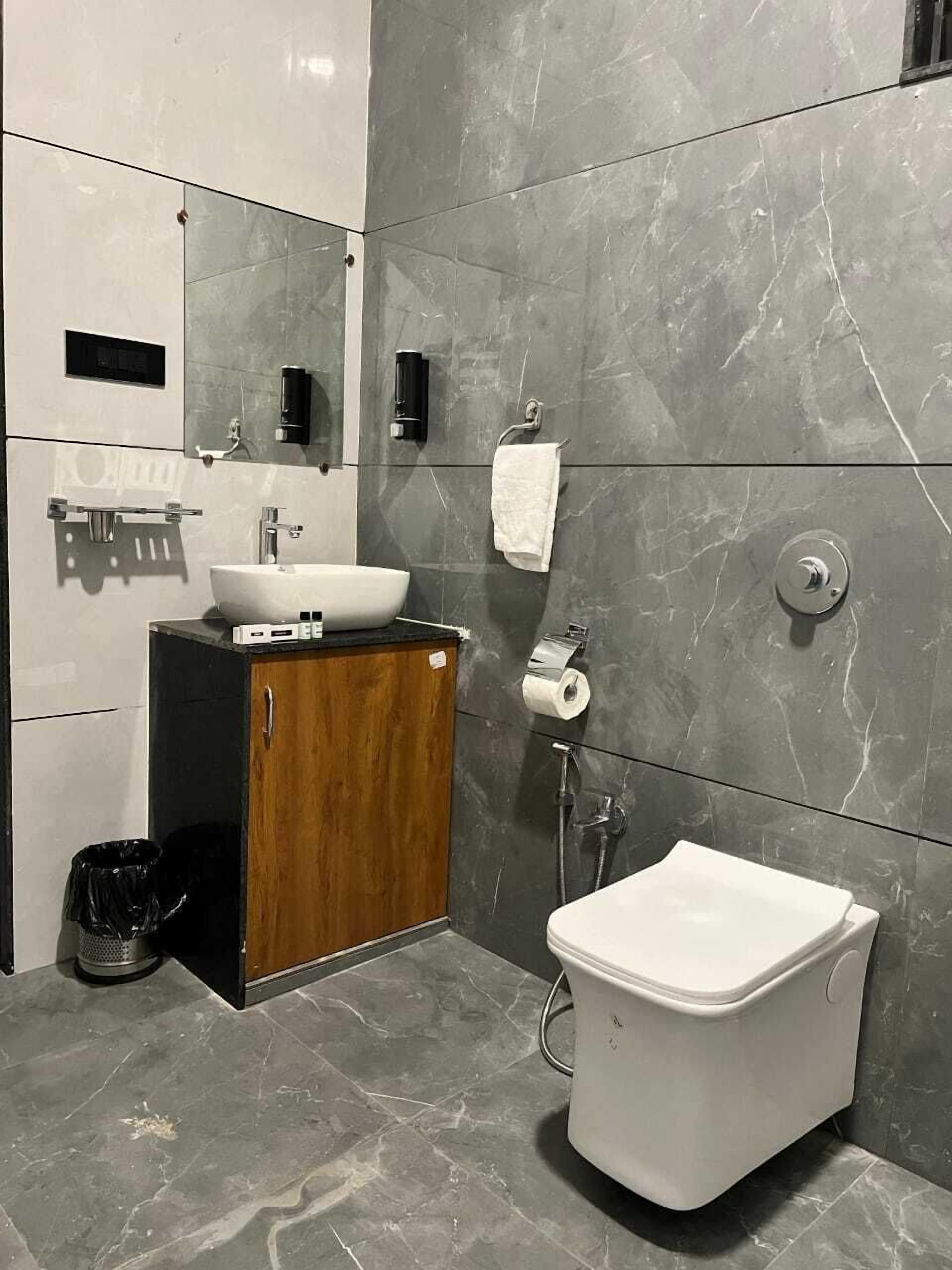 A modern bathroom with a vanity, sink, mirror, and toilet.