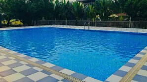 A swimming pool with a checkered tile border and a metal safety ladder. - Gokul Resort  (Talala)