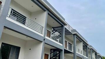 Un edificio moderno de varios pisos con balcones, ventanas amplias y techo plano.