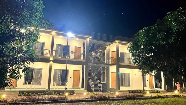 A two-story building with a balcony on the upper floor, a staircase, and a well-lit entrance. - Gokul Resort  (Talala)