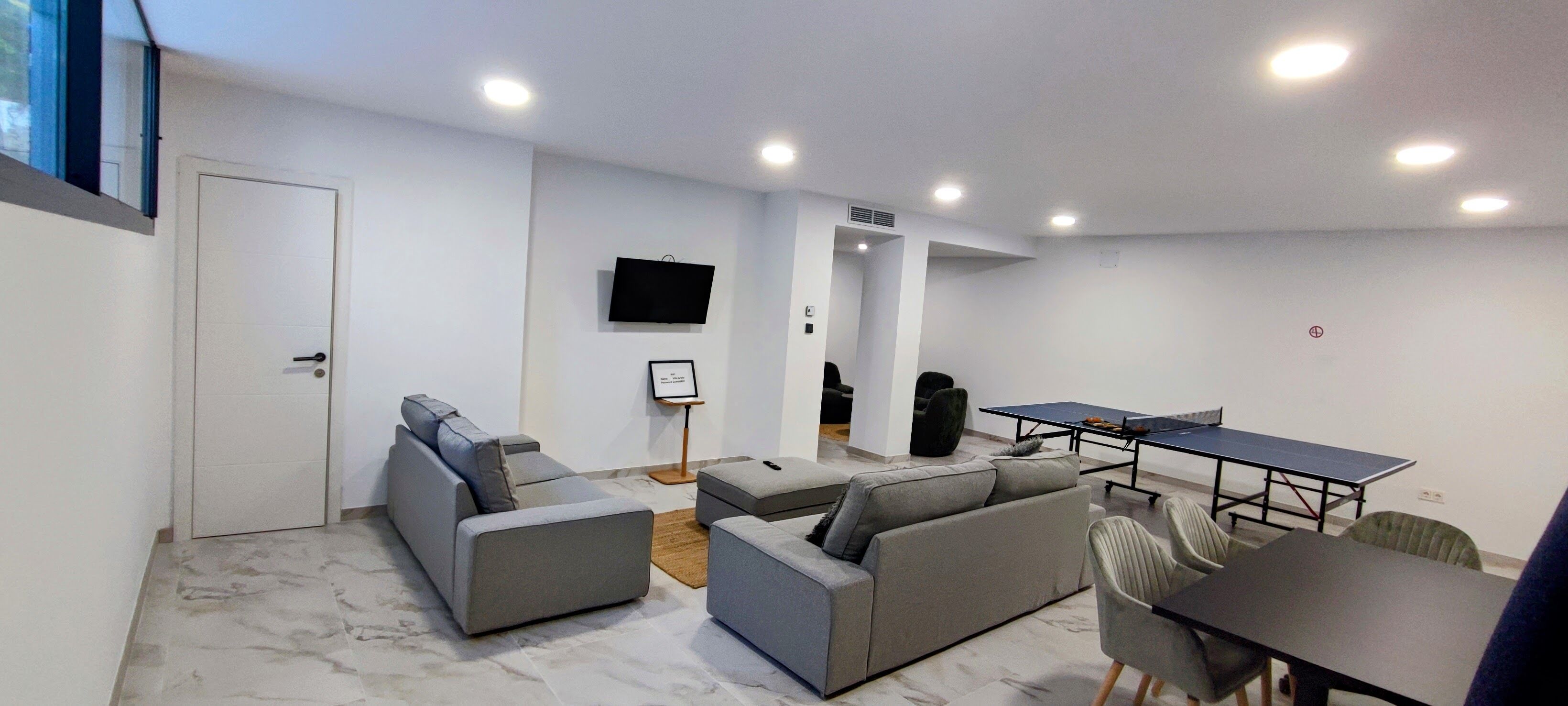 Una sala de estar moderna con un sofá, una mesa de centro, un televisor y una mesa de ping pong.