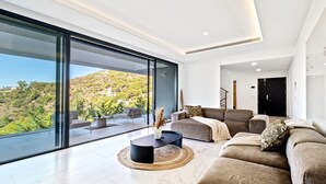 A modern living room with a large glass wall, a sofa set, and a coffee table. - Villas Pinares de San Antón, Saltwater pool, Sea, City, Mountain Views (Málaga)
