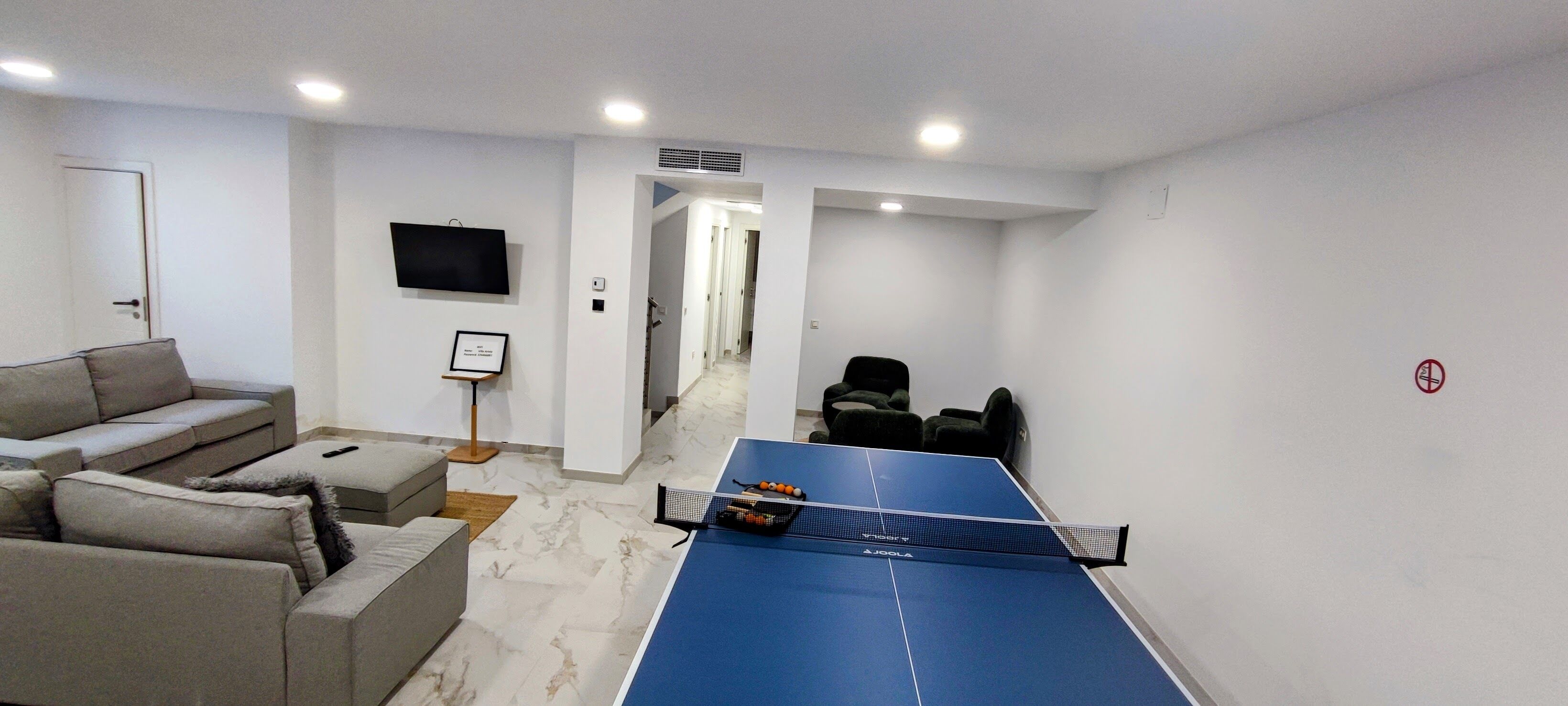 Un salon moderne avec une table de ping-pong, un canapé et un téléviseur.