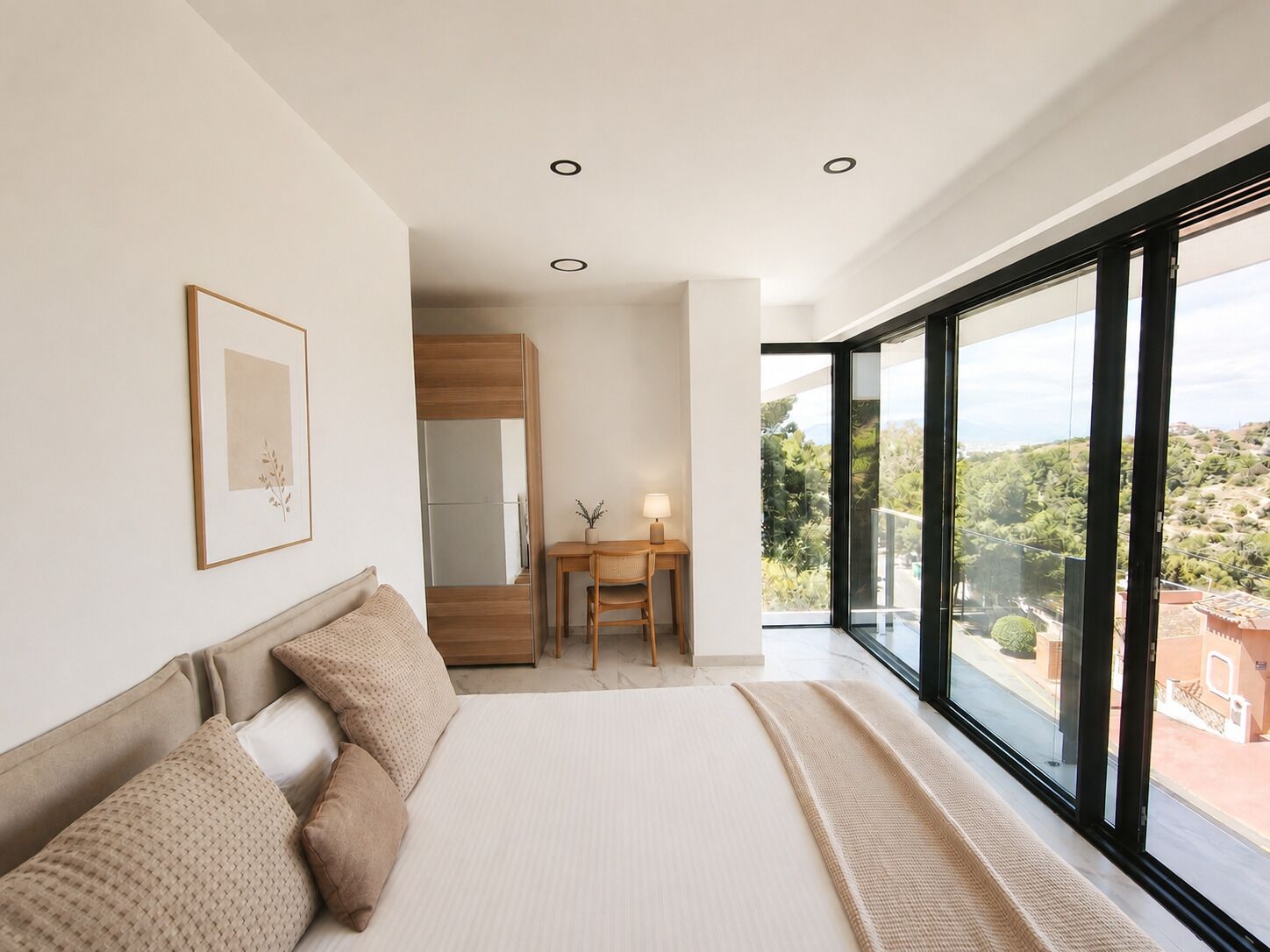 A bedroom with a large bed, a desk, and a view of the outdoors.