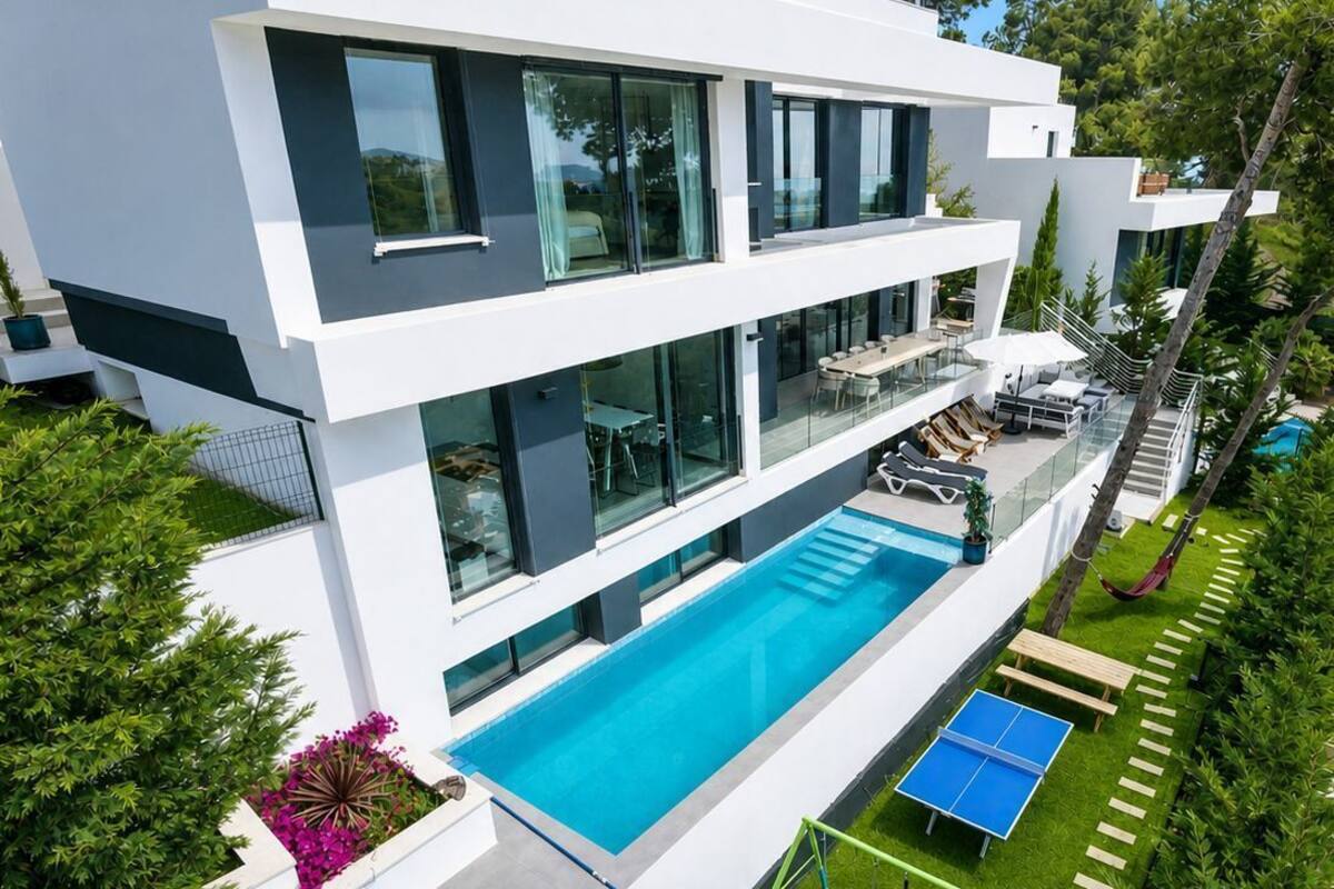 Ein modernes, zweistöckiges Haus mit Swimmingpool, Sitzgelegenheiten im Freien und einer Schaukel.