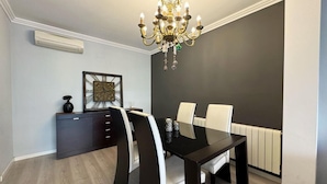 A dining area with a black table, white chairs, a chandelier, and a framed picture on the wall.