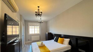 A hotel room with a bed, a television, a desk, and a window.