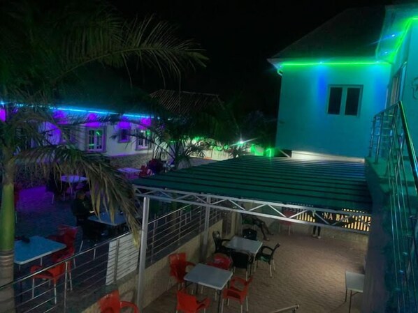 Eine Außenpatio-Terrasse mit Tischen und Stühlen, ein überdachter Sitzbereich und ein Gebäude mit Gründach.