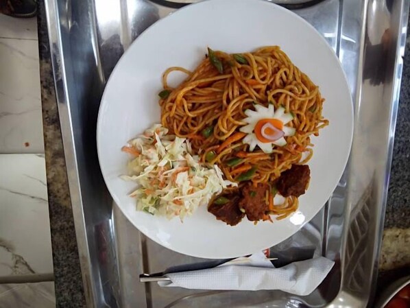 A plate of noodles with vegetables and meat on a white plate. - Ovena Luxury Hotel (Abuja)