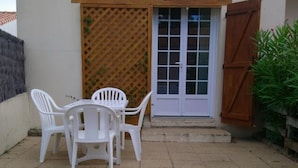 A patio with a white table and chairs, a wooden door, and a lattice wall.