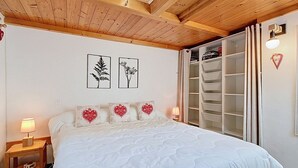 A bedroom with a bed, bedside tables, a wardrobe, and wall art. - La Clusaz: 31m² Apartment, 4 people, South Balcony (La Clusaz)