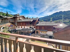A traditional wooden building with a balcony, a sign for a pharmacy, and a view of a mountain.