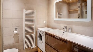 A modern bathroom with a built-in washing machine, a white sink, and a large mirror. - La Clusaz: Studio 4 pers, Balcony, Wifi, Pets allowed (La Clusaz)