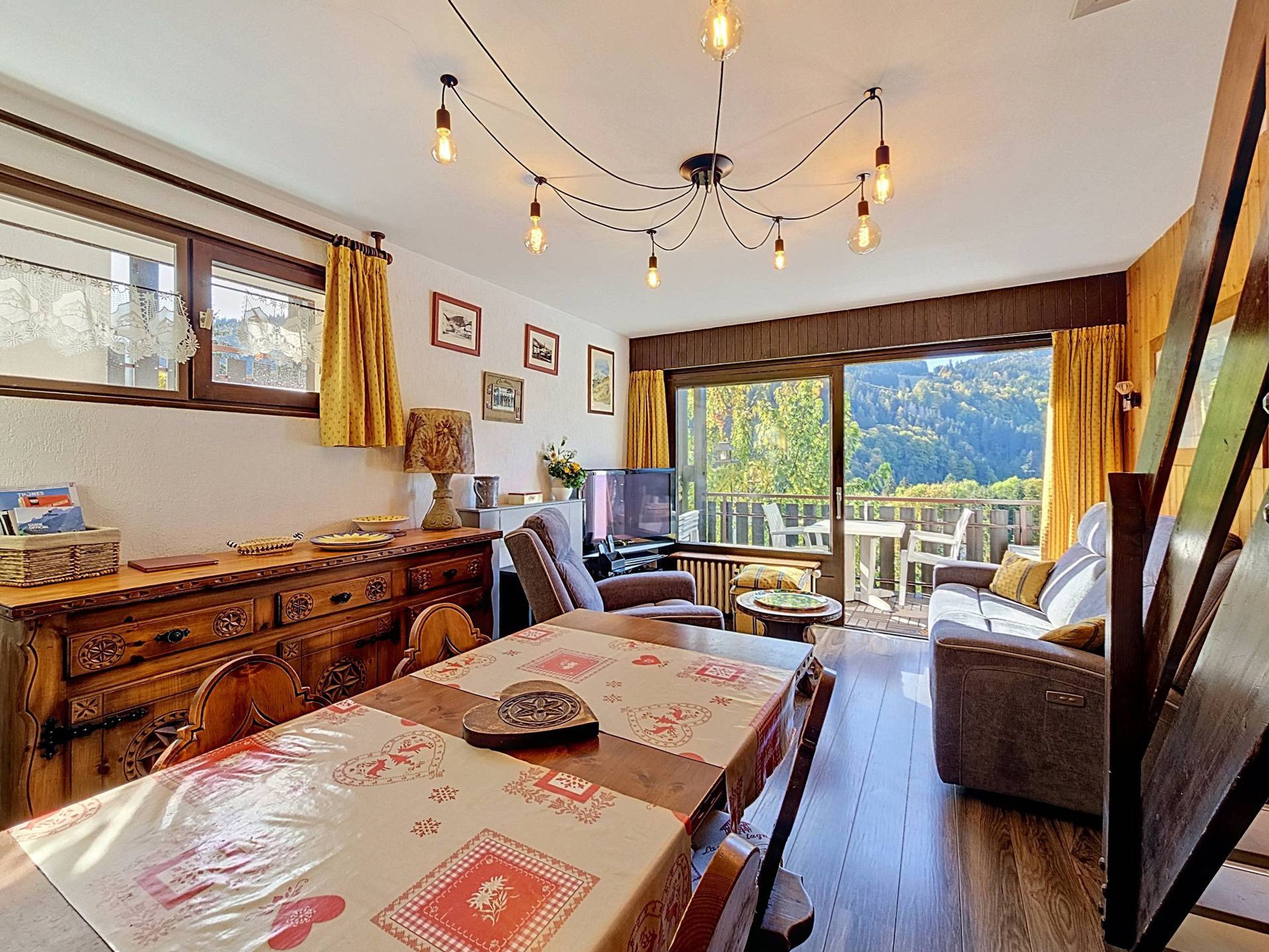 Un coin repas avec une table dressée pour quatre personnes, un meuble en bois et un téléviseur posé sur un meuble.