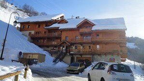 A multi-story wooden building with balconies, a ski lift in the background, and cars parked in front. - 2-room apartment, 4 pers, 4*, parking, Valloire (Valloire)