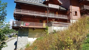 A multi-story wooden building with balconies, stone foundation, and a clear sky. - 2-room apartment, 4 pers, 4*, parking, Valloire (Valloire)