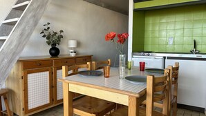 A kitchen with a wooden table, chairs, a stove, and a green backsplash. - 2-Bed Mezzanine Apt - A/C, Parking, Near center (Fleury-Saint-Pierre-la-Mer)