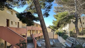 A courtyard with a staircase leading to a building, a bench, and a fence. - 2-Bed Mezzanine Apt - A/C, Parking, Near center (Fleury-Saint-Pierre-la-Mer)