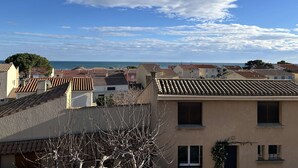 A coastal residential area with terracotta-tiled roofs, a clear sky, and a view of the sea. - 2-Bed Mezzanine Apt - A/C, Parking, Near center (Fleury-Saint-Pierre-la-Mer)