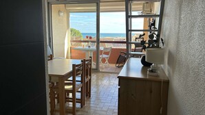 A small kitchen with a dining area and a sliding glass door leading to a balcony with a view of the sea. - 2-Bed Mezzanine Apt - A/C, Parking, Near center (Fleury-Saint-Pierre-la-Mer)