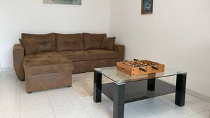 Ein Wohnzimmer mit einem braunen Sofa, einem Glastisch mit Holzfuß und einem gerahmten Bild an der Wand.
