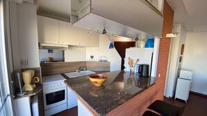A compact kitchen with white cabinets, a granite countertop, a built-in oven, and a sink. - Duplex T3 Sea View, Sleeps 6, Terrace, Parking, Barcarès (Le Barcarès)