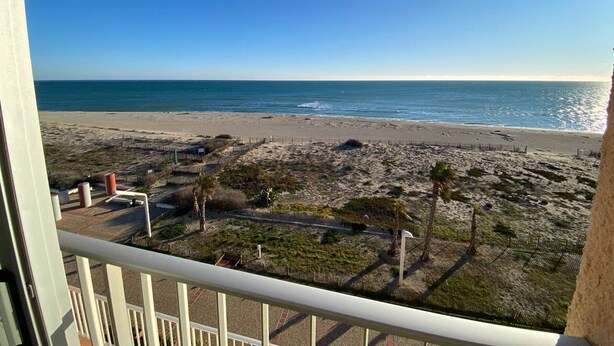 A beach view from a balcony with a clear sky, sandy beach, and sparse vegetation. - Duplex T3 Sea View, Sleeps 6, Terrace, Parking, Barcarès (Le Barcarès)