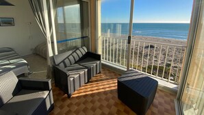 A balcony with wicker furniture, a view of the beach, and a large sliding glass door. - Duplex T3 Sea View, Sleeps 6, Terrace, Parking, Barcarès (Le Barcarès)