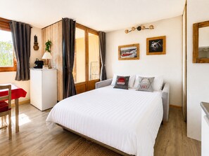 A bedroom with a bed, a desk, a chair, and a window with curtains. - Modern and bright studio with views of Mont Charvin. Private parking (Notre-Dame-de-Bellecombe)